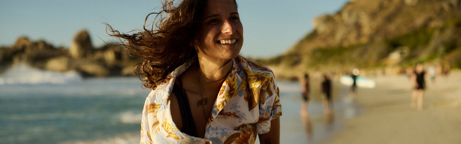 Kobieta stosująca specjalistyczną podpaskę uśmiecha się na plaży w słoneczny dzień