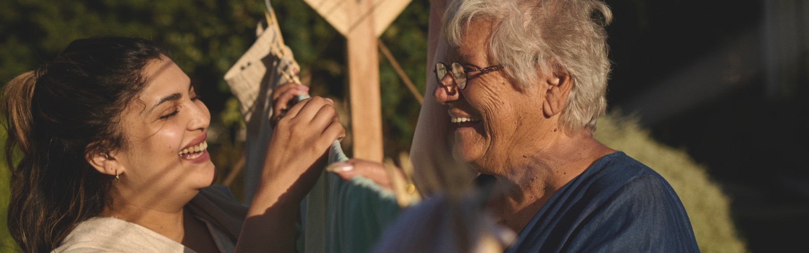 Zwei Frauen lachen, während sie sich über einer Wäscheleine unterhalten.