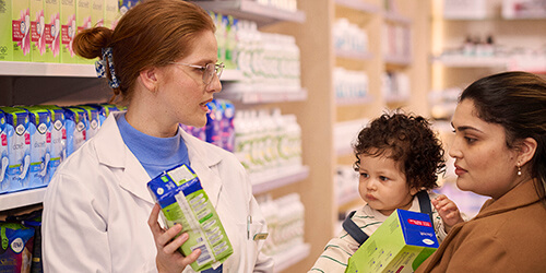 TENA-Women-Lifestyle-Pharmacist-showing-TENA-product-to-Mother-with-small-child-Promobox-500x250px                                                                                                                                                                                                                                                                                                                                                                                                                  