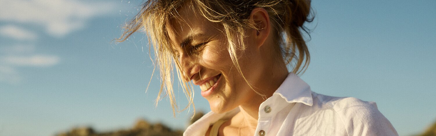 Kobieta stosująca specjalistyczną wkładkę uśmiecha się na plaży w słoneczny dzień