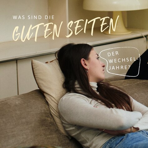 Aby and her female friend are in conversation on the sofa. Text reads: What’s the best thing about the menopause? I’ve changed so much in a positive way, I’m less ambiguous as to who I am.