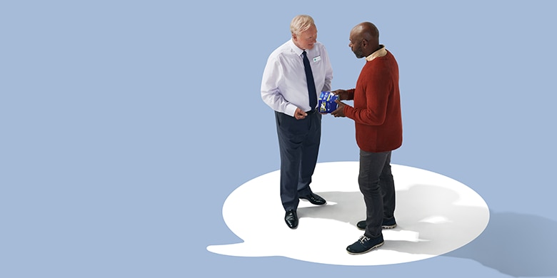 Two men holding and discussing a TENA product