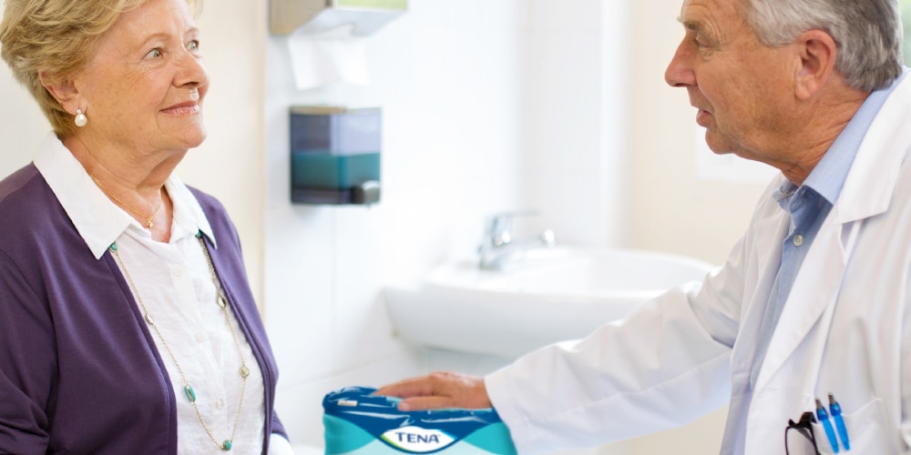 A doctor discusses TENA ProSkin Pants with his elderly female patient.