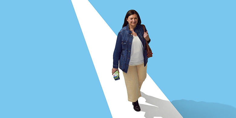 A woman walking while holding a TENA product