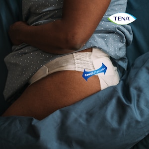 Osoba leží naboku na posteli s oblečenou pomôckou TENA Proskin Flex a je viditeľná technológia ComfiStretch™