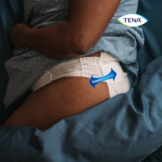 Person som ligger på sidan i sängen med produkten TENA Flex på. Produktens COMFIStretch™-teknik visas.